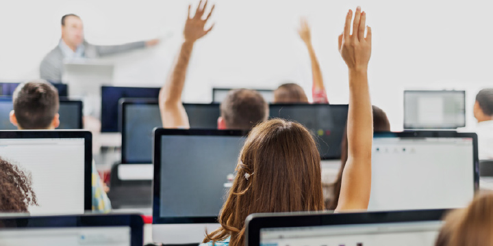 image of students raising their hands in a classroom