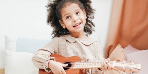 Photograph of a young child playing a ukulele