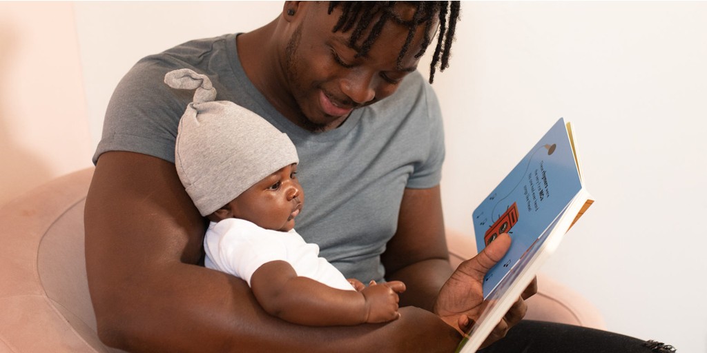 Photograph of a man reading to a baby