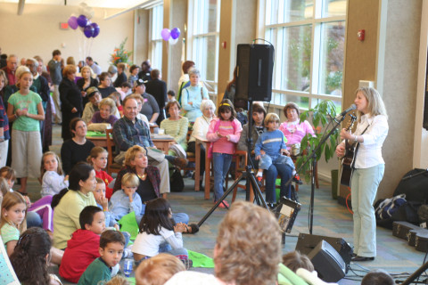 A large group of patrons enjoy a musical performance in the library.
