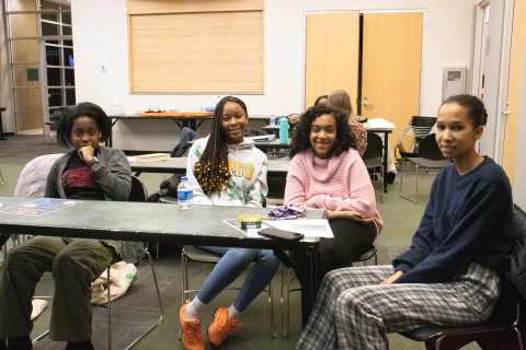 Four teens sit side-by-side smiling at the camera.