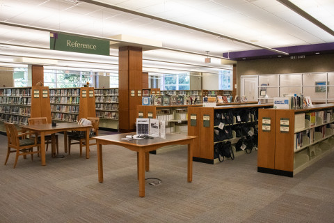A wide-angle photograph features several shelves of books, a Quiet Reading Room in the background, and some tables and chairs in the foreground.