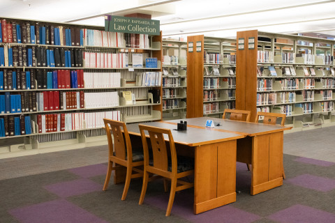 A wide-angle photograph features several shelves of books. A sign hanging above the shelves reads, 