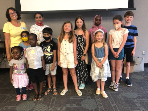 Author Meg Medina poses with a group of tweens and children at a library book discussion.