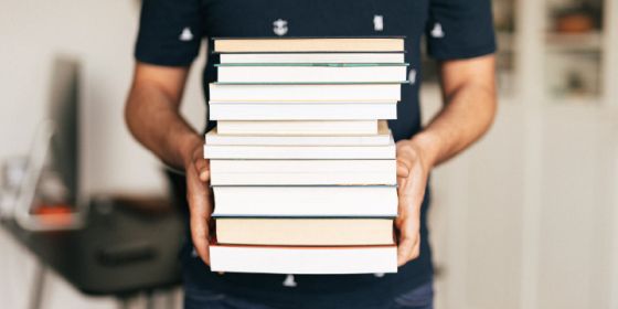 image of a person carrying a stack of books