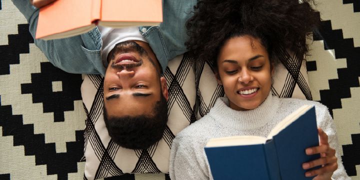 Man and woman lying on the floor reading books